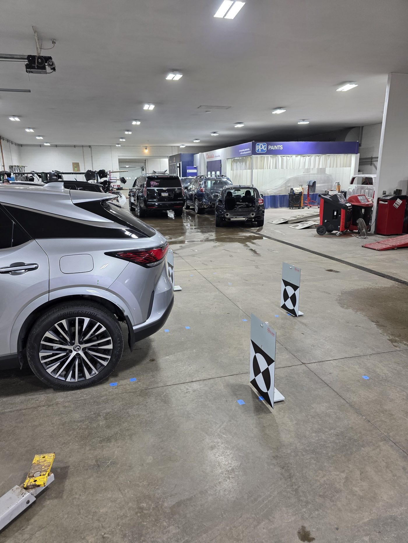 Silver Lexus SUV positioned with checkerboard ADAS calibration targets in a body shop