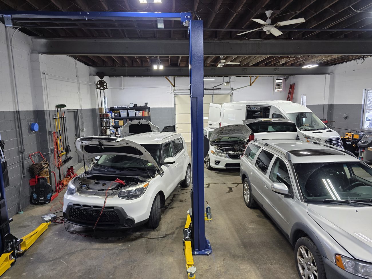 Auto repair shop bay with a two-post lift and vehicles undergoing service
