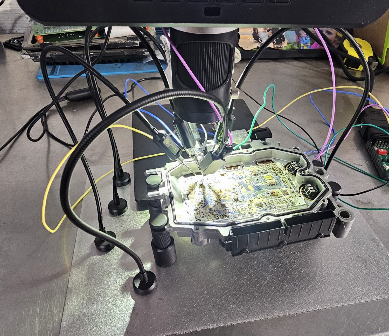 Control module circuit board under microscope with test leads for board-level repair and bench diagnostics
