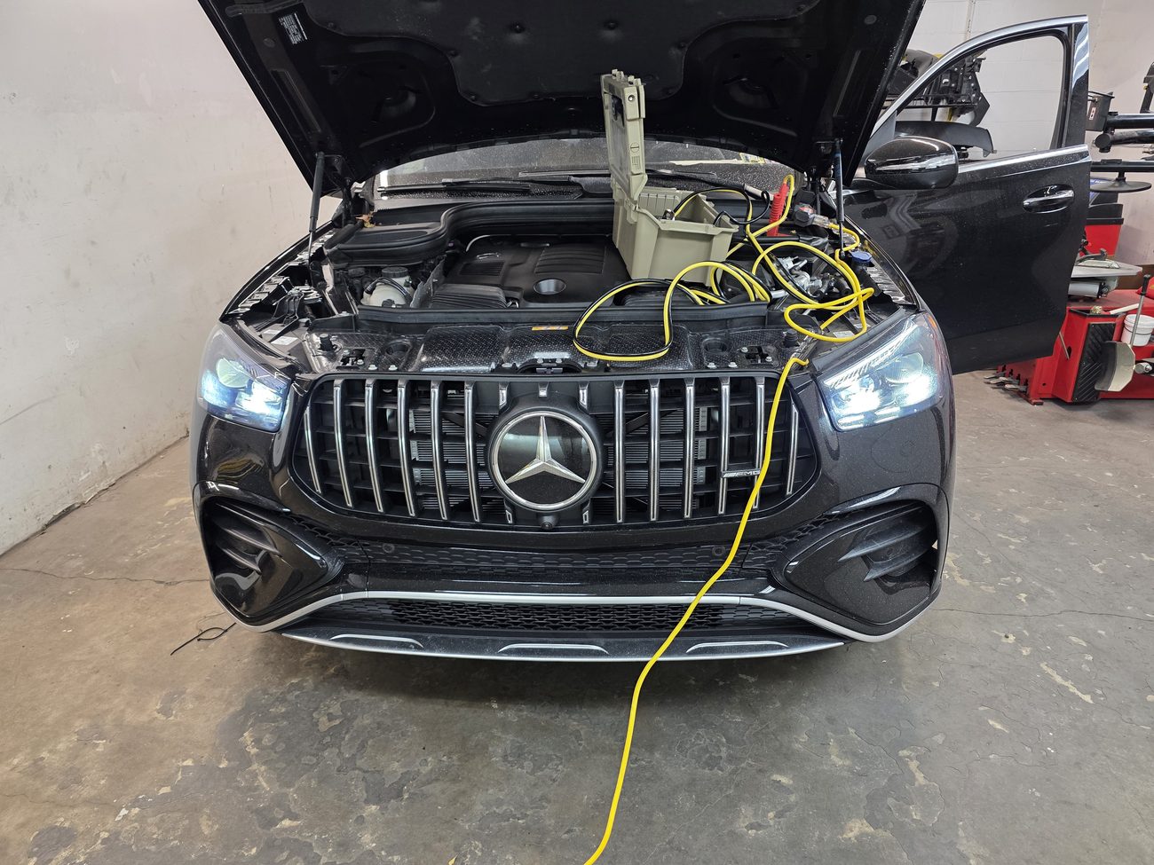 Black Mercedes-AMG SUV connected to programming leads and a battery support unit