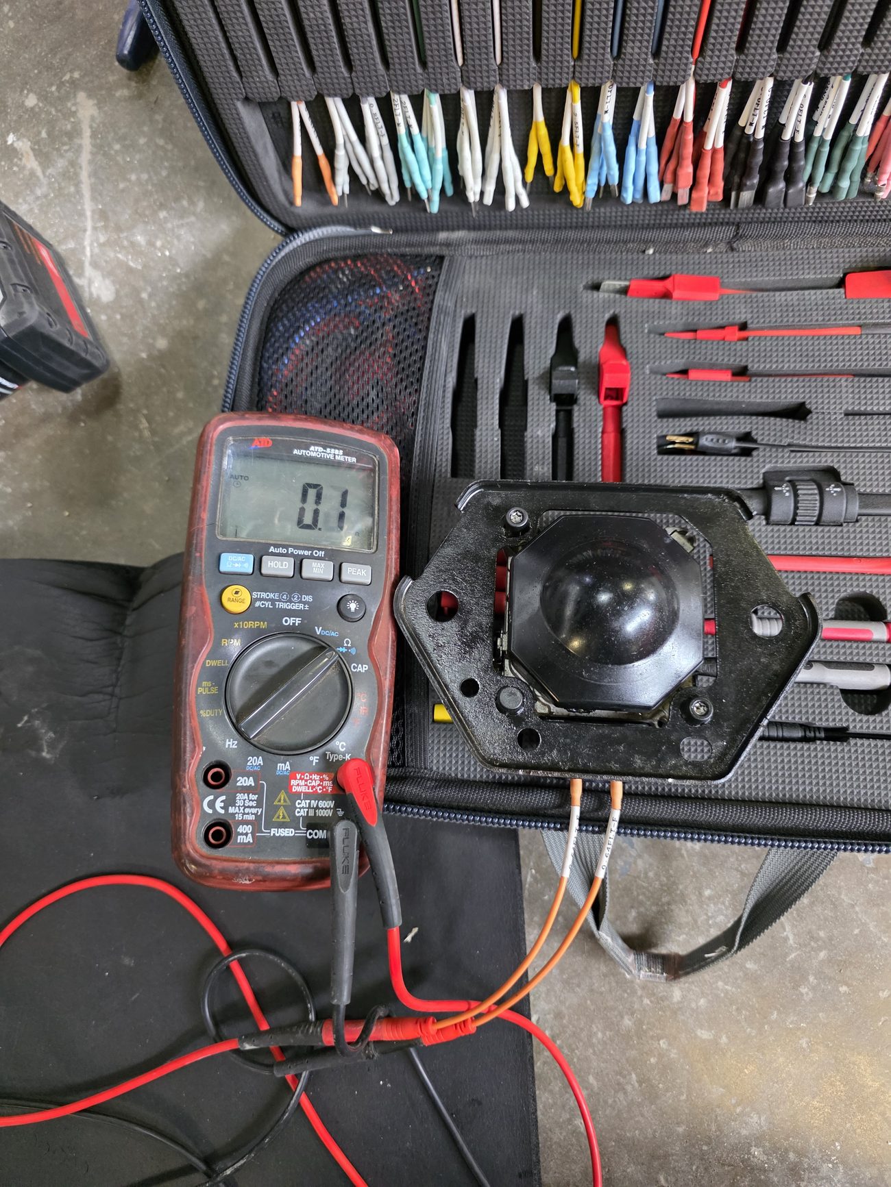 Multimeter and back-probe test leads used to measure an automotive component circuit