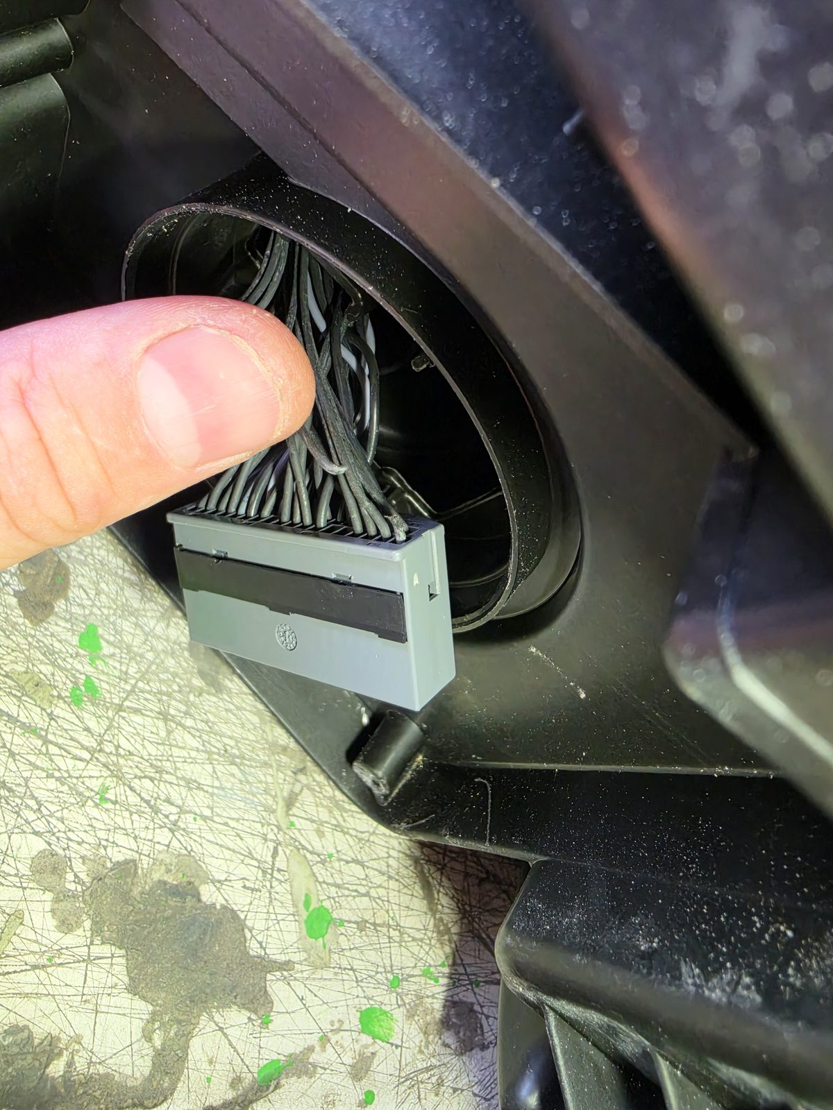 Technician pointing to a multi-pin electrical connector during vehicle wiring diagnostics