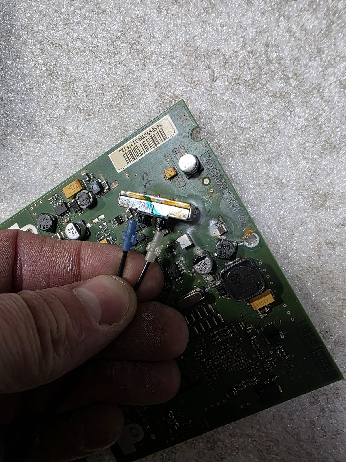Technician holding a vehicle control module board during board-level repair